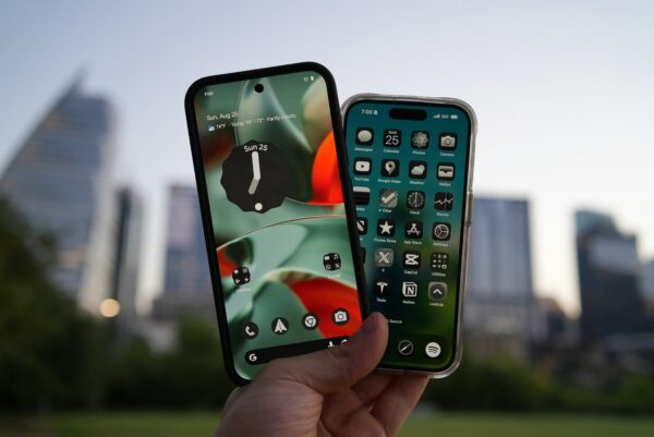 Photo by Daniel Romero Two smartphones held up against city skyline